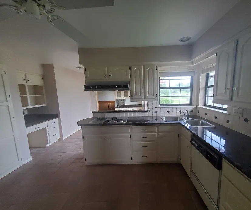 Kitchen with white cabinets and dark countertops before the remodel