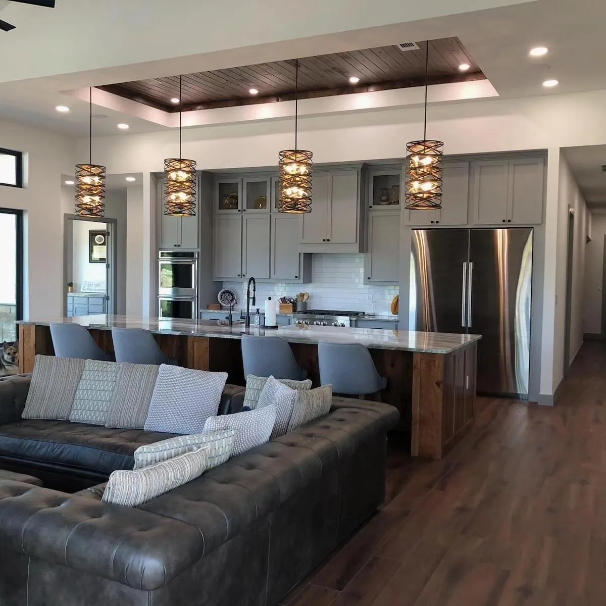 Open-plan kitchen and living room with pendant lights over the island and a grey sectional sofa