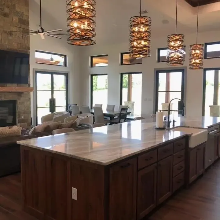Kitchen island with a stone countertop and farmhouse sink, open to the living room and fireplace