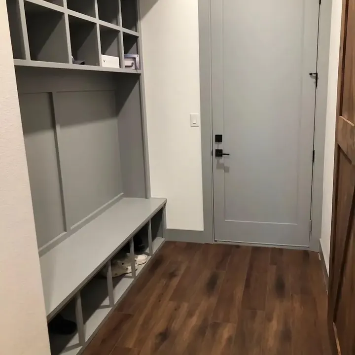 Mudroom bench with cubbies beside a grey door