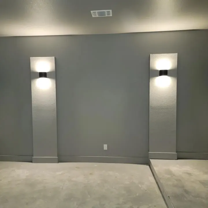 Grey media room wall with two lit wall sconces