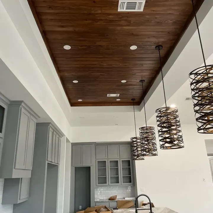 Wood-plank tray ceiling with recessed lights over grey kitchen cabinets and spiral pendant lights